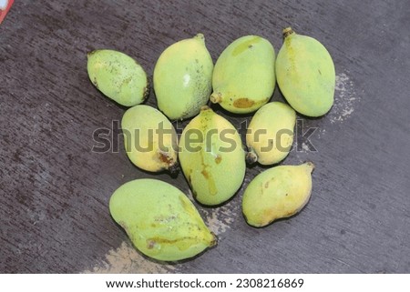A picture of some fresh young mangoes on a wooden table