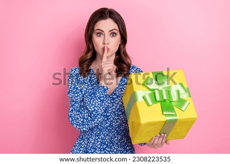 Photo of pretty girl hold giftbox finger cover lips demonstrate shh gesture isolated on pink color background
