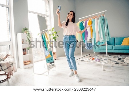 Photo of positive lady shopaholic open her online boutique with hanger garment welcome buying in showroom