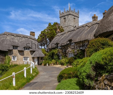 The tower of All Saints Church and beautiful thatched cottages in the picturesque village of Godshill on the Isle of Wight, UK. Royalty-Free Stock Photo #2308252609