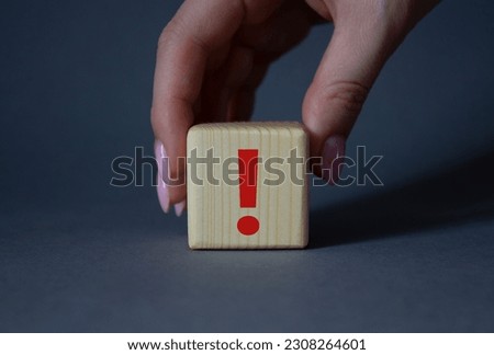 Exclamation mark symbol. Exclamation mark on wooden cubes. Businessman hand. Beautiful grey background. Business and Exclamation mark concept. Copy space.