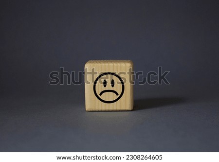 Sad smile symbol. Sad smile on wooden cube. Beautiful grey background. Business and Sad smile concept. Copy space.