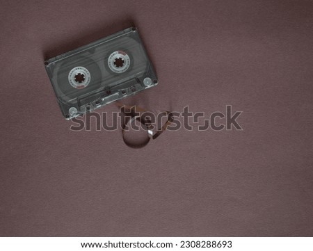 Audio cassette with tangled tape on a dark background, top view.