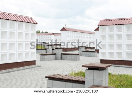 Rows of white walls for the burial of ashes after cremation. Empty cells for urns with ashes. Benches for relaxation near the columbarium