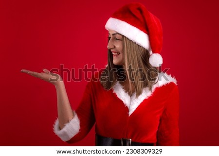 Very beautiful adult woman wearing Santa's hat and dress, in studio shot with red background, with space for text and making various facial expressions