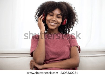 Above view of lovely African American lady taking selfie while listening to music in headphones at home. Listening and enjoying sound, audio podcast or song. Dreaming time.