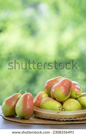 Red Pear ang Green Pear on bamboo basket under sunlight on blurred nature background.