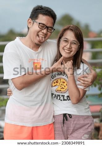Asian couple with eyeglasses and wearing simple white t-shirts enjoying the company of each other. Royalty-Free Stock Photo #2308349891
