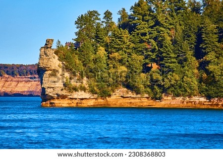 Sapphire lake and green summer forest over stone cliffs of Pictured Rocks island or peninsula