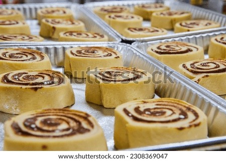 Fresh pre-baked cinnamon rolls in silver trays Royalty-Free Stock Photo #2308369047