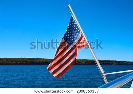 American flag hanging off boat with distant shore and calm lake or river waters