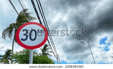 traffic sign, 30 km speed limit, with overcast clouds in the background