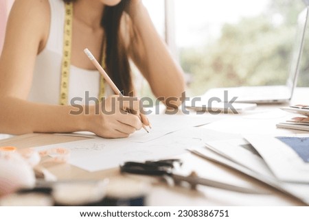 Closeup beautiful hand young adult women designer sketching idea with pencil. Workplace table with design fashion equipment
