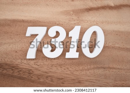 White number 7310 on a brown and light brown wooden background.