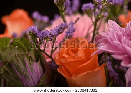 Beautiful orange roses surrounded by stunning floral arrangement in a studio setup on a reflective surface with light from behind. Inspirational as roses are the flower of love