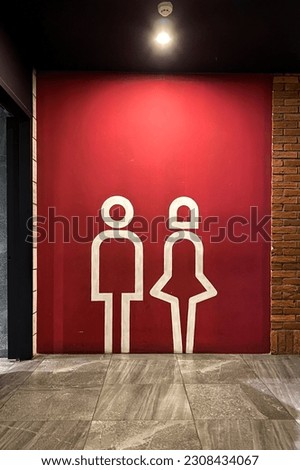 Men and women sign with red background at public restroom or toilet