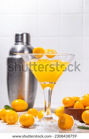 Kumquat martini cocktail, non-alcohol mocktail, tropical citrus fruit drink in martini glass, with sliced and whole kumquat and mint on table background copy space Royalty-Free Stock Photo #2308438759