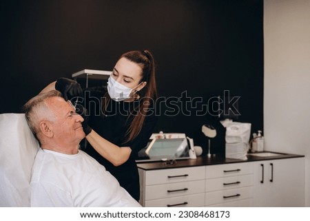 an old man makes an injection for wrinkles in a beauty salon.