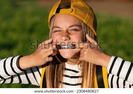 Portrait of beautiful young blonde girl in a yellow cap and a bracket on her teeth.