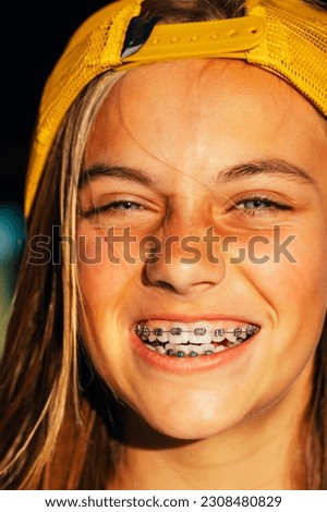 Portrait of beautiful young blonde girl in a yellow cap and a bracket on her teeth.