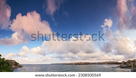 panorama with fluffy clouds on a blue sky in evening light. beautiful nature background at the sea. warm weather in velvet season