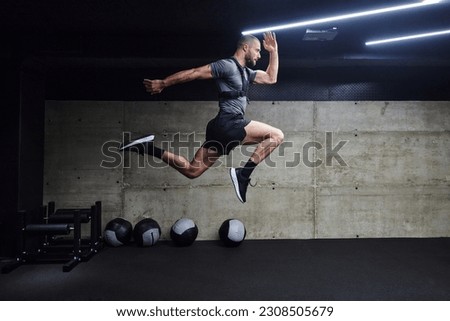 A muscular man captured in air as he jumps in a modern gym, showcasing his athleticism, power, and determination through a highintensity fitness routine Royalty-Free Stock Photo #2308505679