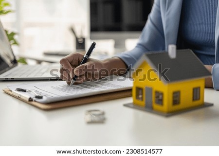Home sales office, female employees inspect the lease agreement and small yellow house to prepare to meet customers to sign the lease agreement. Real Estate Rental Ideas