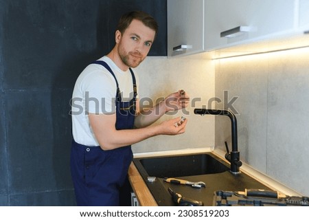 Professional plumber fixing water tap in kitchen.