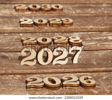 nature wooden numbers in the sun on a sunny day. 
create 2027 with 2026 and 2028 2029 2030.
background is made from naturally wood.
celebrate a friendly atmosphere on happy new year celebrations Royalty-Free Stock Photo #2308521039