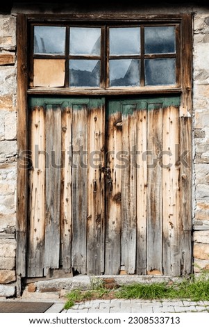 Old wooden plank gate of barn with glass top facade, front view