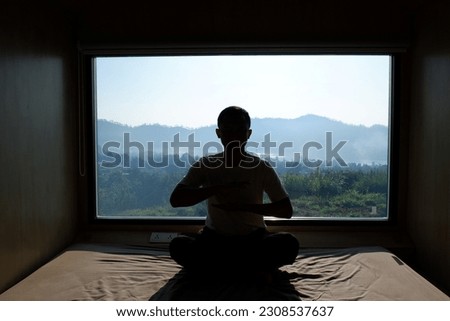Silhouette of Asian man doing yoga with landscape background. Selective focus