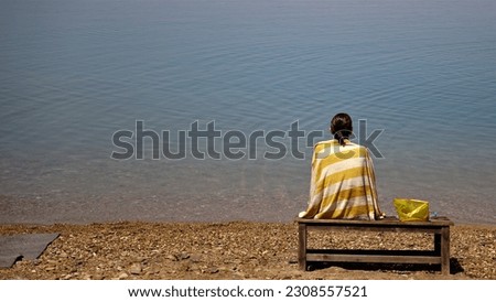 girl with back covered with towel looking at sea Royalty-Free Stock Photo #2308557521