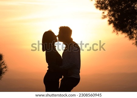 Silhouette of kissing couple against sunset at mountain top. Romantic scene of lovers kiss. Romance and activities for in love people in Saint Valentine's Day, Spain..