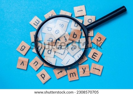 English alphabet made of square wooden tiles with the English alphabet scattered on blue background. The concept of thinking development, grammar. Royalty-Free Stock Photo #2308570705