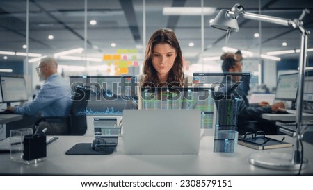 Young Happy Businesswoman Using Laptop Computer in Modern Office with Colleagues. Stylish Beautiful Financial Advisor Working. VFX Hologram Edit Visualizing Stock Exchange Interface, Opened Charts.