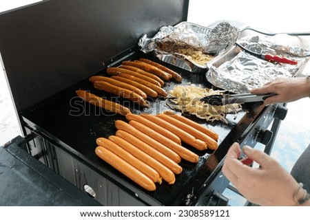 An unrecognisable person cooking a traditional australian bbq sausage sizzle, sausages cooking on a barbeque Royalty-Free Stock Photo #2308589121