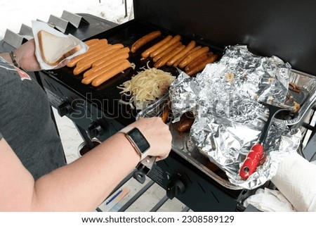 An unrecognisable person cooking a traditional australian bbq sausage sizzle, sausages cooking on a barbeque Royalty-Free Stock Photo #2308589129
