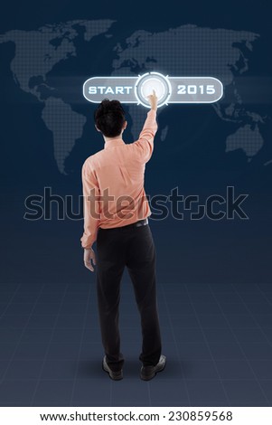 Rear view of businessman touching a virtual button to start his business in 2015