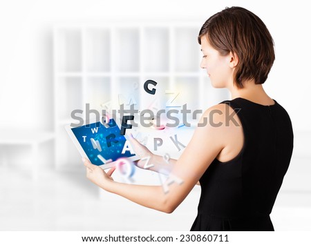 Beautiful young woman looking at modern tablet with alphabet 