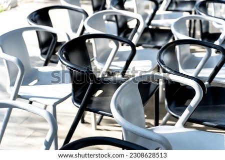 White and black iron chairs are lined up in alternating colors.