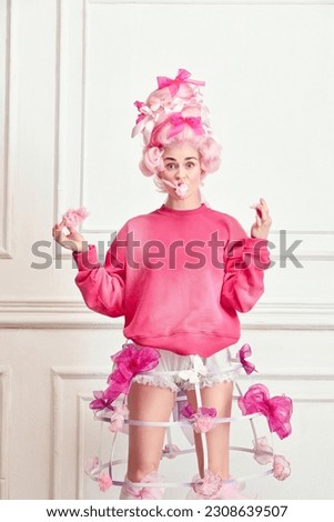 Sugar diet. Portrait of charming girl, princess wearing pink wig and eating sweet cotton over luxury interior background. Concept of comparison of eras, modernity and renaissance, beauty, history Royalty-Free Stock Photo #2308639507