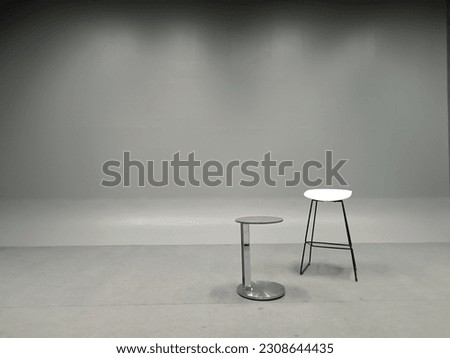 a white chair and a tall table in an empty room