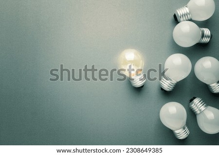 Transparent small light bulb glowing in the group of the white light bulbs, different and original idea Royalty-Free Stock Photo #2308649385