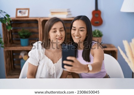 Two women mother and daughter make selfie by smartphone at home