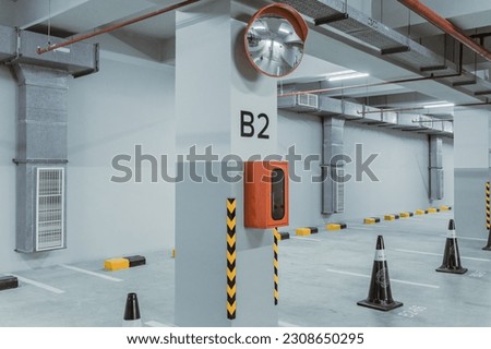 Modern indoor parking lot area with sign, stripes, and cone. Indoor car parking floor.