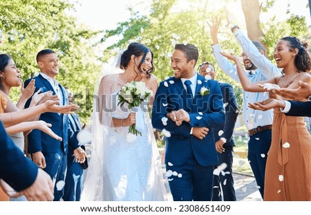 Happy, wedding ceremony and couple walking with petals and guests throw in celebration of romance. Romantic, flowers and bride with bouquet and groom with crowd celebrating at outdoor marriage event. Royalty-Free Stock Photo #2308651409