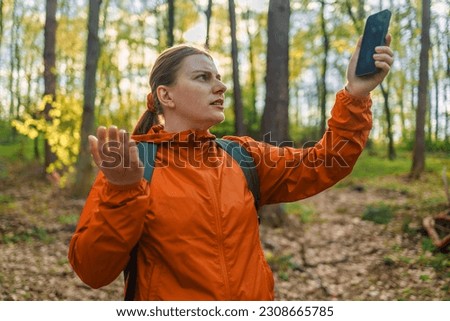 Angry woman tourist hiker hand holding smart phone searching signal in the forest. Communication, cellular problem, bad connection. No signal cellphone network. No communication coverage, lost contact Royalty-Free Stock Photo #2308665785