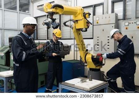 Teamwork of male engineer using laptop computer inspecting quality automatic robotic arm at production line in industry factory. Male technician worker checking and control automatic robot arm