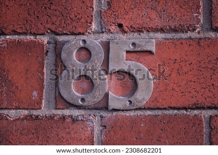 Worn metal door number 85 attached to a brick wall