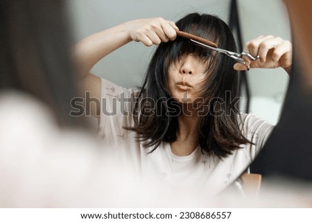 Haircut. Beautiful asian woman is going to cut her hair by herself. Women's haircut and hairdresser. Bangs hair. Close up hairstyle with bangs. Royalty-Free Stock Photo #2308686557